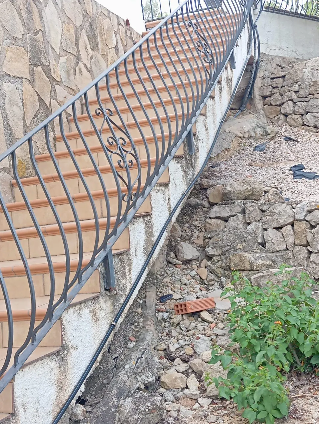 Escalera exterior y muro de piedra antes de reparar